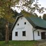 White vacation home with green roof in the forest, labeled 'Haltberghof'.