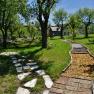 A barefoot path with different materials in a green garden with trees and a hammock.